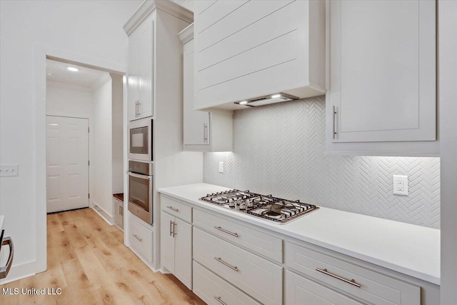 961 Mullican Rd, Florence, MS 39073 - kitchen featuring appliances with stainless steel finishes, backsplash, light countertops, white cabinetry, and light wood-style flooring