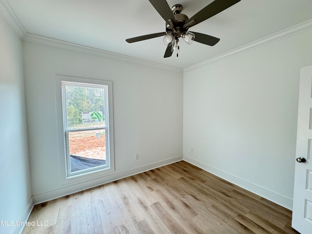 spare room featuring crown molding, baseboards, and wood finished floors