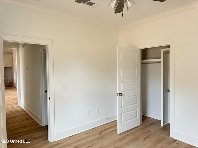 unfurnished bedroom featuring visible vents, baseboards, ornamental molding, light wood-type flooring, and a closet