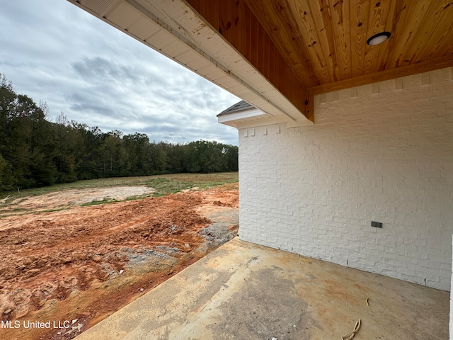 view of property exterior featuring a view of trees and brick siding