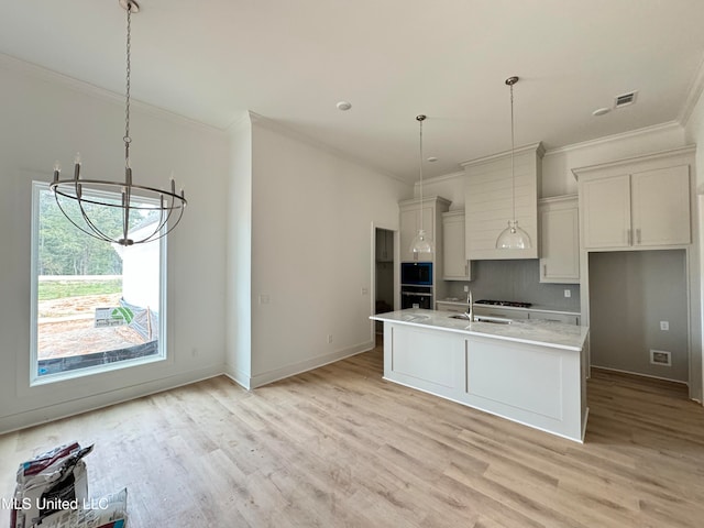 kitchen with light countertops, light wood-style flooring, a kitchen island with sink, stainless steel oven, and white cabinetry