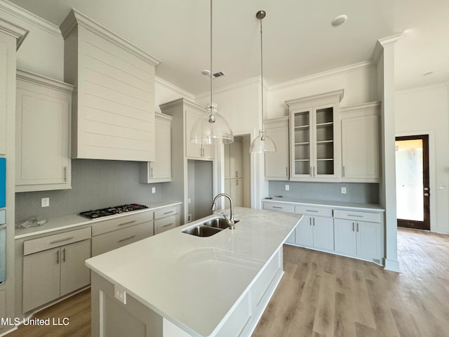 kitchen featuring light countertops, a sink, gas stovetop, and light wood-style floors