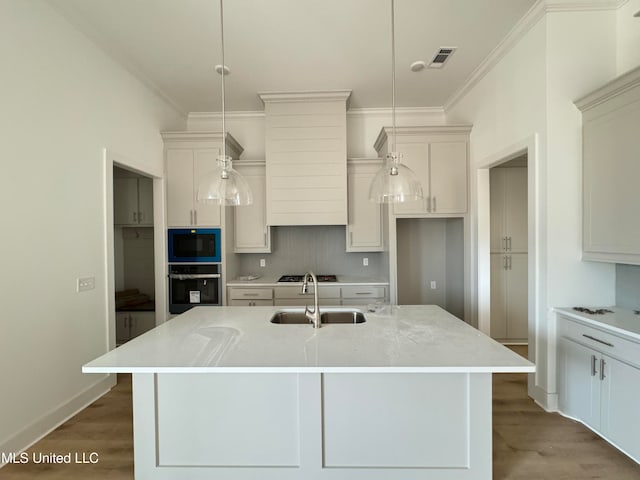 kitchen featuring visible vents, wall oven, a sink, wood finished floors, and black microwave