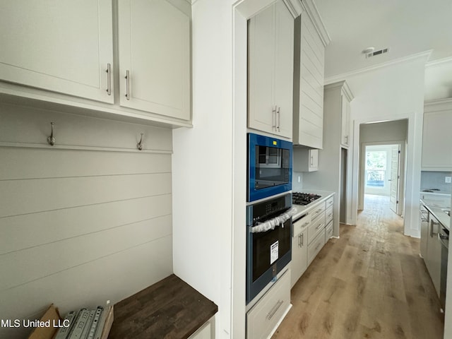 kitchen with gas stovetop, visible vents, stainless steel oven, light wood-type flooring, and black microwave