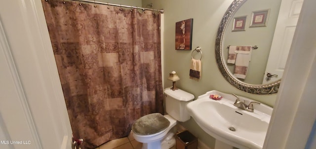 bathroom with toilet, walk in shower, sink, and tile patterned flooring