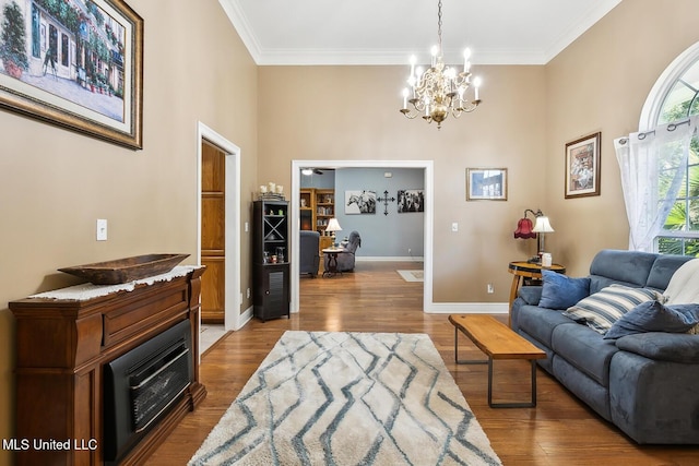 living room with crown molding, wood-type flooring, and an inviting chandelier