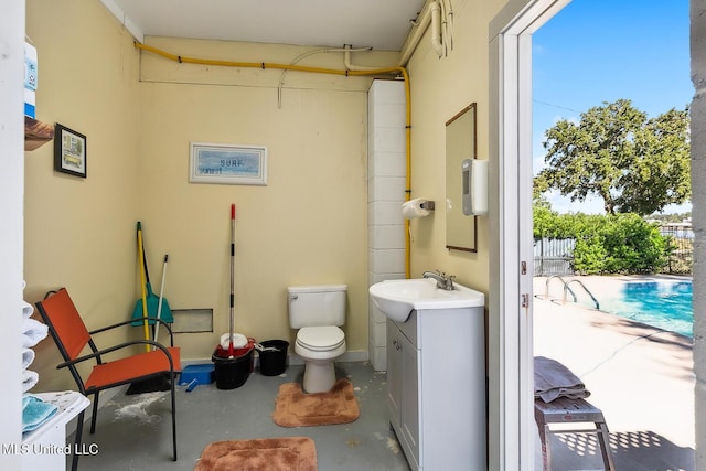 bathroom with vanity, toilet, and concrete flooring