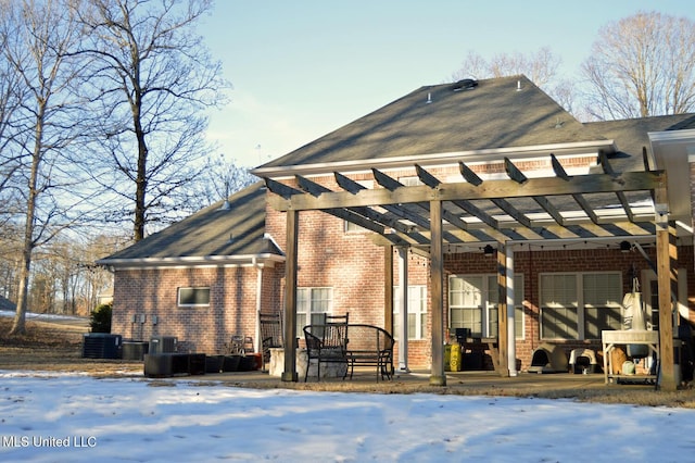 snow covered house with a patio area, central AC unit, and a pergola