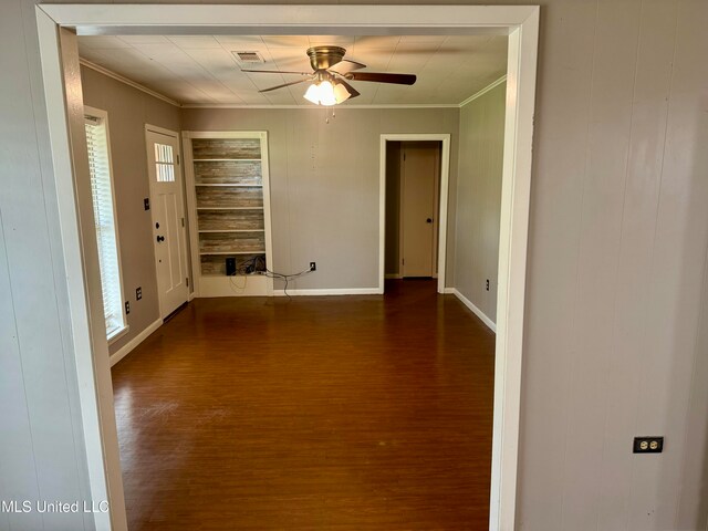 empty room featuring crown molding, a healthy amount of sunlight, ceiling fan, and dark hardwood / wood-style flooring