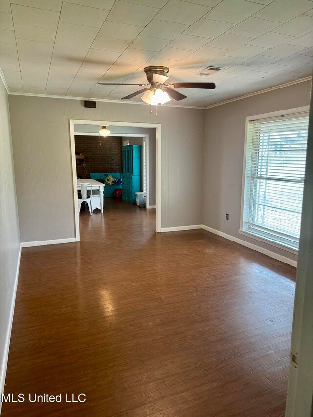 empty room with ceiling fan, crown molding, and dark hardwood / wood-style floors