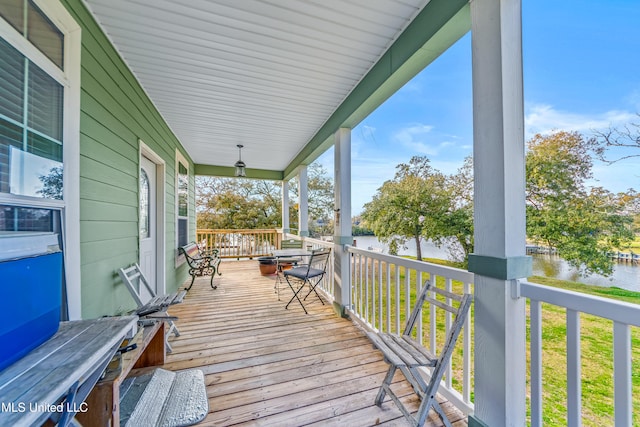 deck with covered porch and a water view