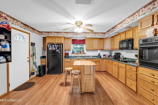 310 John Ave, Pascagoula, MS 39567 - kitchen with black appliances, a textured ceiling, light wood finished floors, ceiling fan, and a breakfast bar
