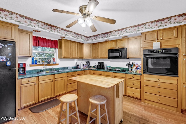 310 John Ave, Pascagoula, MS 39567 - kitchen with black appliances, a sink, light wood-style floors, a breakfast bar, and wooden counters