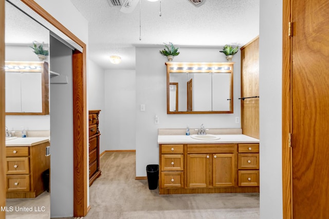 310 John Ave, Pascagoula, MS 39567 - bathroom featuring two vanities, a ceiling fan, a textured ceiling, and baseboards