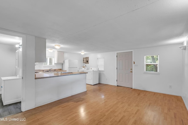 310 John Ave, Pascagoula, MS 39567 - kitchen featuring freestanding refrigerator, a sink, light wood finished floors, a peninsula, and white cabinetry