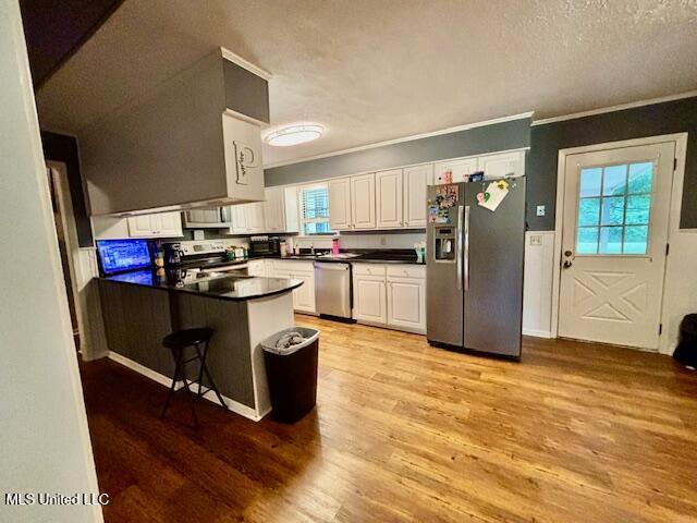 149 Martin Cir, Mendenhall, MS 39114 - kitchen featuring appliances with stainless steel finishes, dark countertops, white cabinets, a peninsula, and crown molding