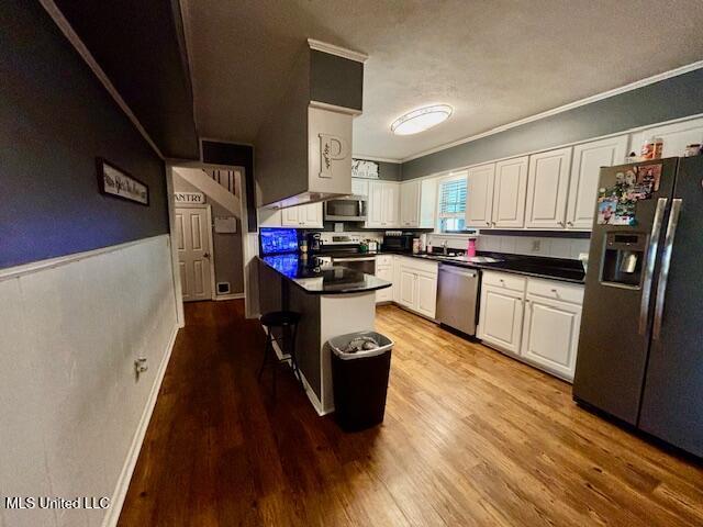 149 Martin Cir, Mendenhall, MS 39114 - kitchen with stainless steel appliances, white cabinetry, ornamental molding, dark countertops, and light wood-style floors