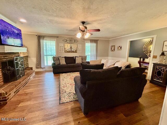 149 Martin Cir, Mendenhall, MS 39114 - living area featuring crown molding, a brick fireplace, a textured ceiling, wood finished floors, and a ceiling fan