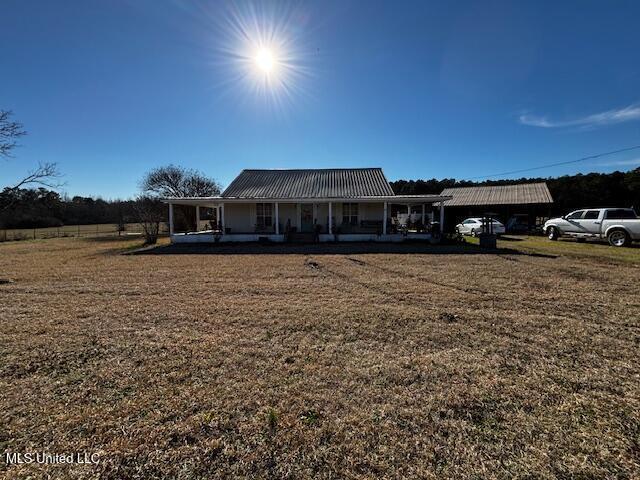 view of front of house featuring a carport, covered porch, and a front yard