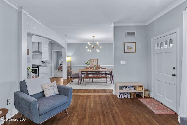 foyer with wood-type flooring, ornamental molding, and a chandelier