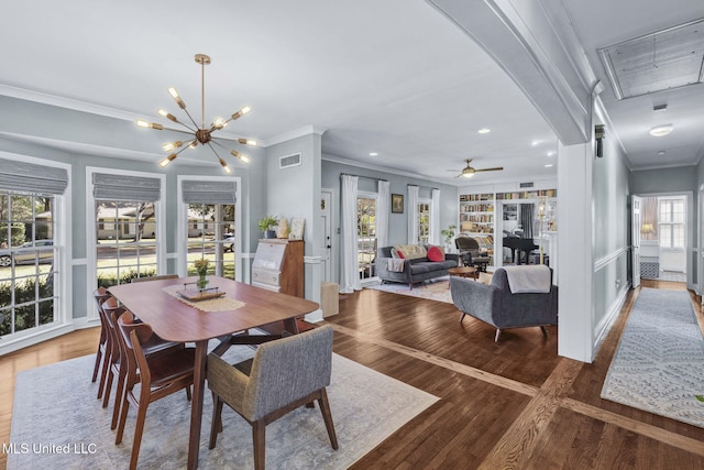 dining area featuring ceiling fan with notable chandelier, built in features, ornamental molding, and plenty of natural light