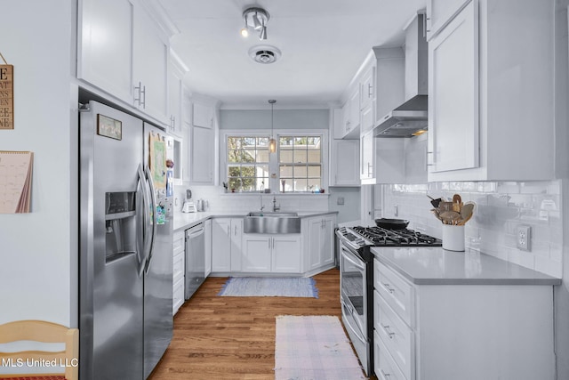 kitchen featuring wall chimney range hood, stainless steel appliances, sink, and white cabinets