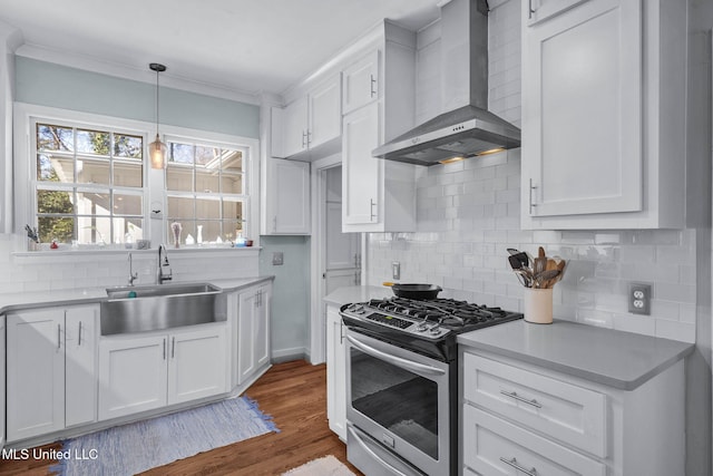 kitchen featuring white cabinets, stainless steel range with gas cooktop, sink, and wall chimney range hood