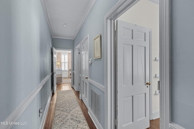 hallway featuring ornamental molding and hardwood / wood-style floors