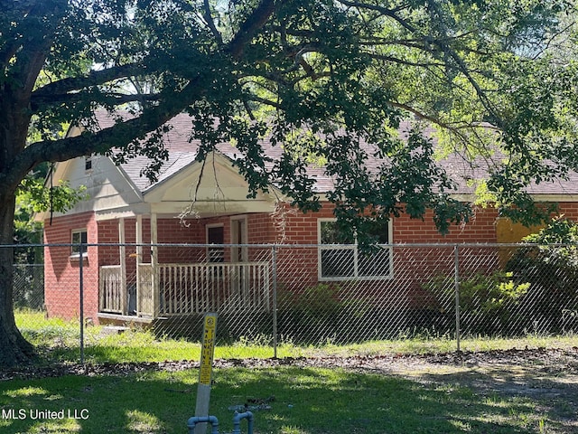 rear view of property featuring brick siding, fence, and roof with shingles