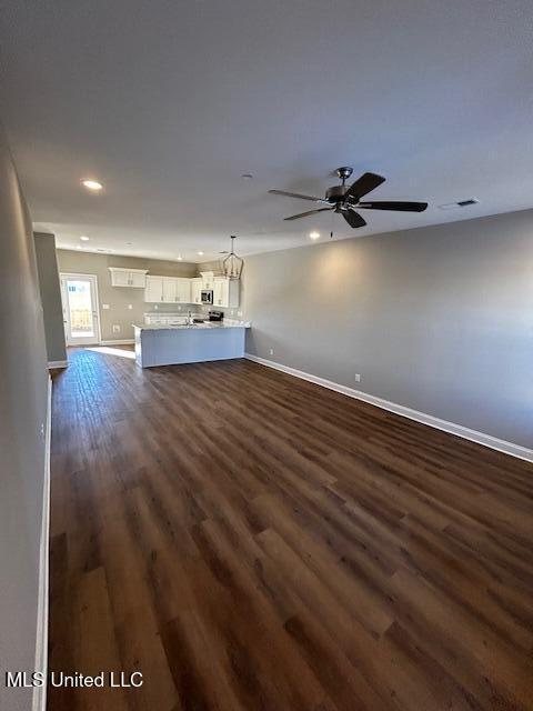 unfurnished living room featuring dark hardwood / wood-style flooring and ceiling fan