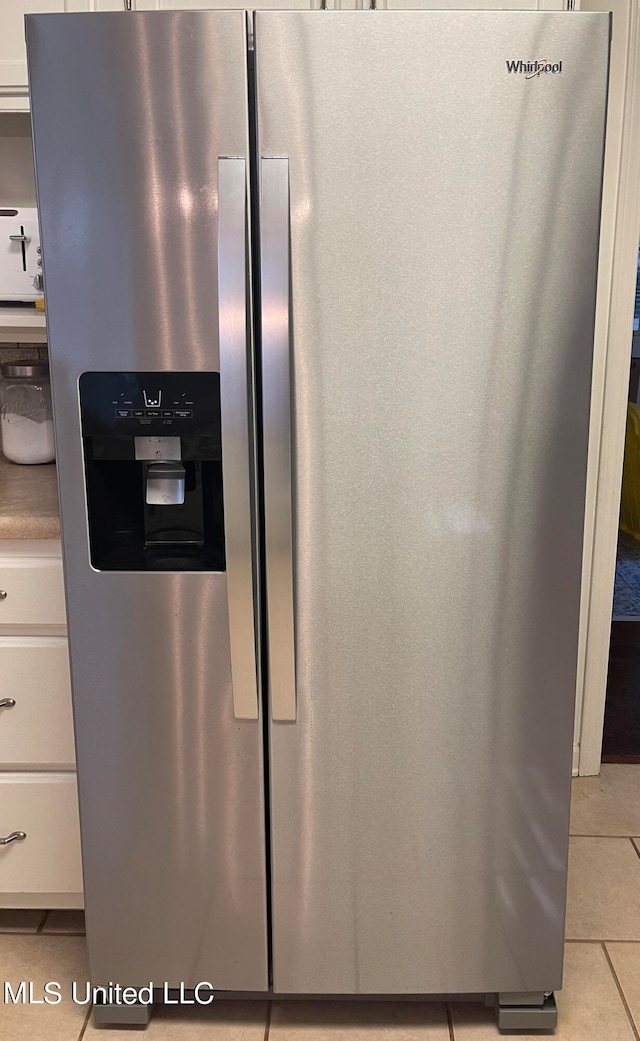 details featuring white cabinets, light tile patterned floors, and stainless steel fridge