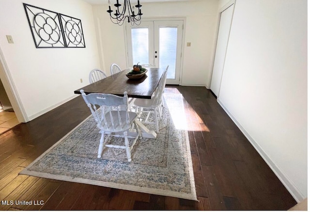 dining area featuring dark wood-type flooring, french doors, and a chandelier