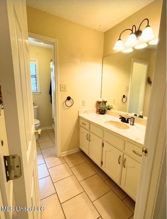 bathroom featuring vanity, toilet, a textured ceiling, and tile patterned flooring