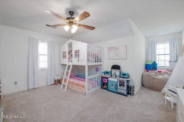 carpeted bedroom with ceiling fan, a textured ceiling, and multiple windows