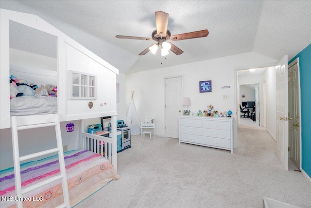 carpeted bedroom with lofted ceiling, a textured ceiling, and ceiling fan