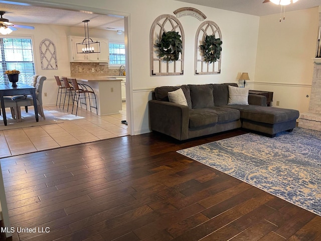 living room featuring a fireplace, light wood-type flooring, and ceiling fan with notable chandelier