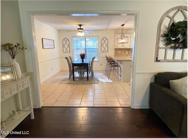 dining room featuring a textured ceiling, light hardwood / wood-style flooring, and ceiling fan with notable chandelier