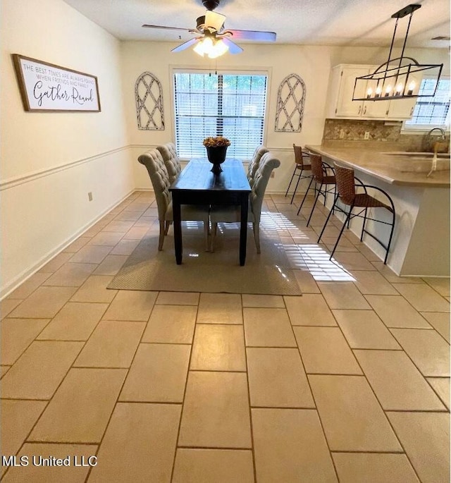 tiled dining room featuring ceiling fan and sink