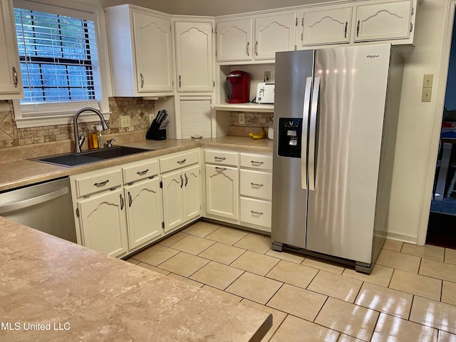 kitchen featuring tasteful backsplash, light tile patterned floors, white cabinetry, sink, and stainless steel appliances