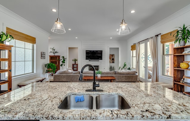 kitchen with light stone counters, open floor plan, and a sink