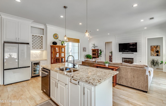 kitchen with freestanding refrigerator, open floor plan, white cabinetry, and a sink