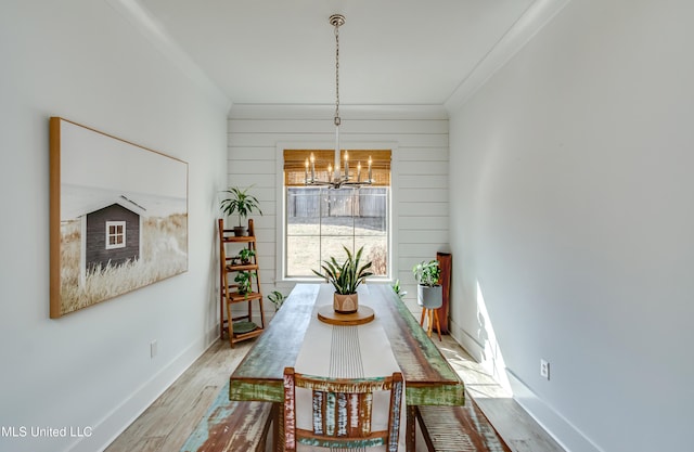 dining area with ornamental molding, baseboards, a notable chandelier, and light wood finished floors