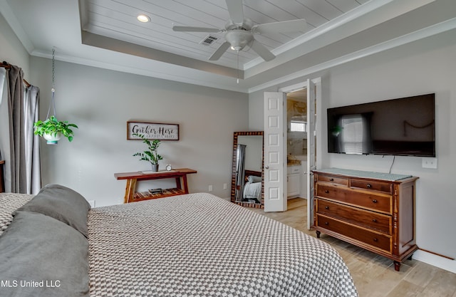 bedroom featuring ornamental molding, a raised ceiling, visible vents, and light wood-style floors