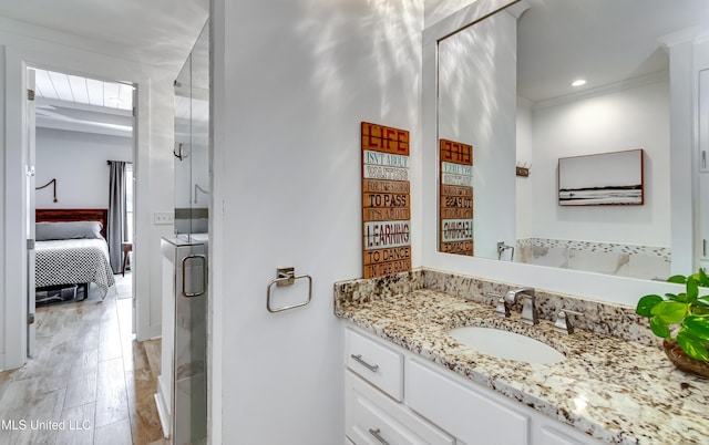 bathroom with connected bathroom, recessed lighting, wood finished floors, vanity, and a stall shower