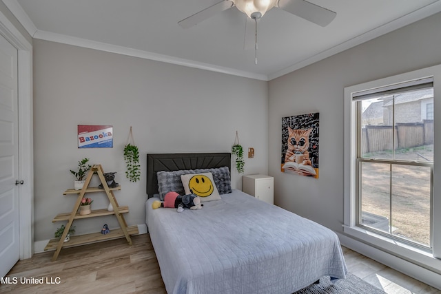 bedroom featuring a ceiling fan, baseboards, crown molding, and light wood finished floors