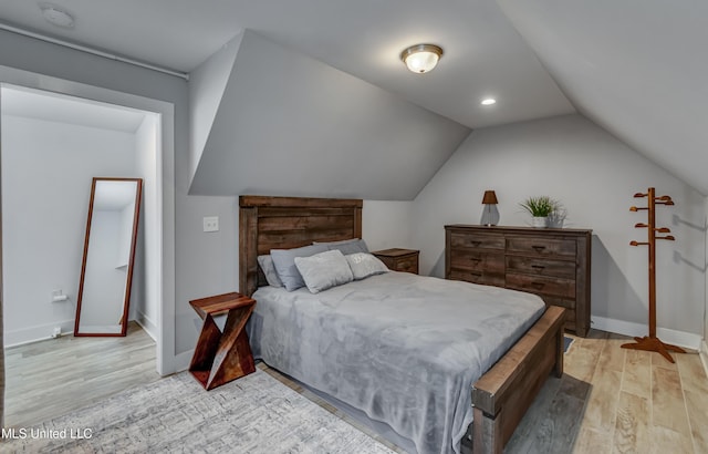 bedroom with vaulted ceiling, light wood-style flooring, and baseboards