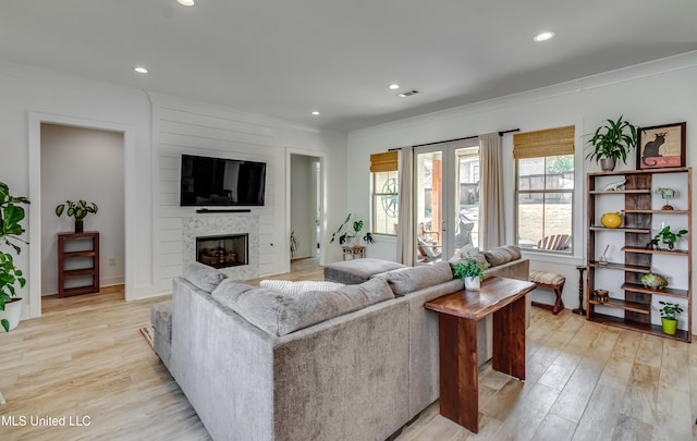 living area featuring crown molding, a fireplace, light wood-style flooring, and recessed lighting