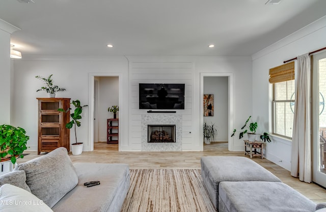 living room with a large fireplace, ornamental molding, light wood-style floors, and recessed lighting