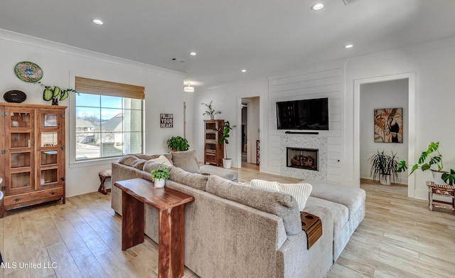 living area with recessed lighting, a fireplace, and light wood-style floors