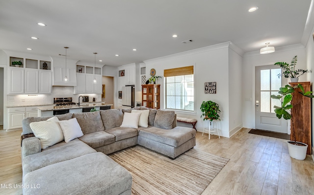 living room with light wood-type flooring, visible vents, crown molding, and recessed lighting